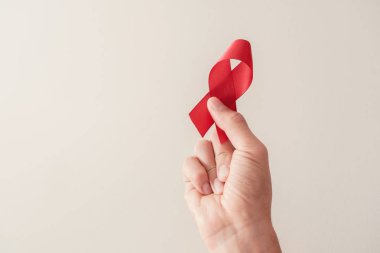 Kırmızı arka planda el ele tutuşan kırmızı kurdele, HIV farkındalığı kavramı