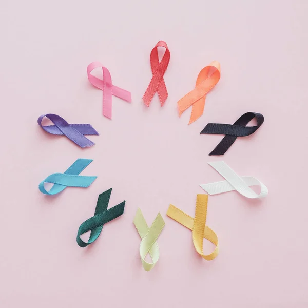 Cintas de colores sobre fondo rosa, conciencia del cáncer, el mundo puede — Foto de Stock