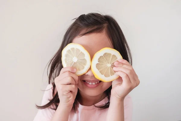 Портрет счастливой маленькой девочки, покрывающей глаза ломтиком — стоковое фото