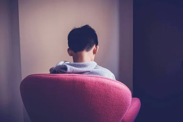Sad preteen tween mixed Asian boy sitting alone in a big chair f — Stock Photo, Image
