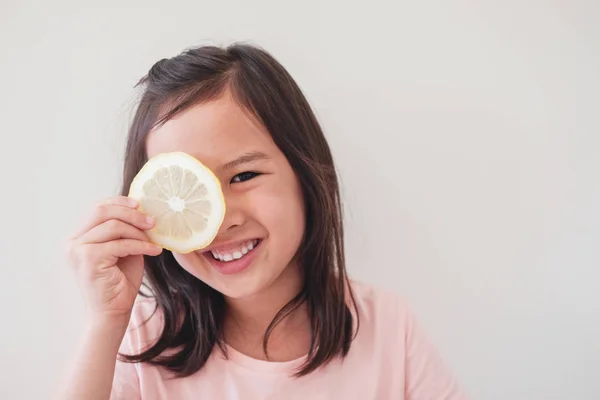 Portrait of happy young little girl covering her eye with slice — Stockfoto