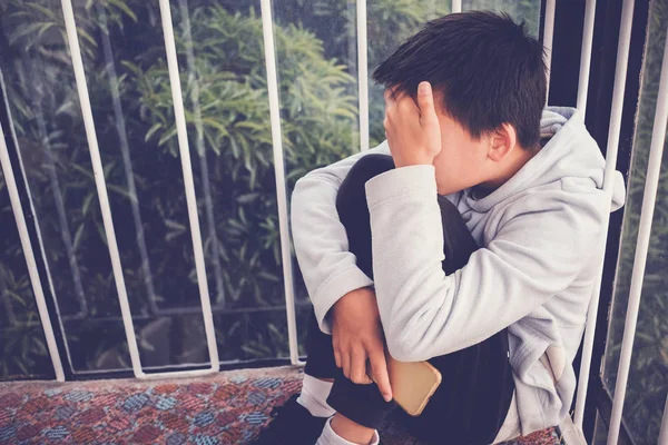 Young Asian preteen teenager boy hugging his knee and cover his — Stock Photo, Image