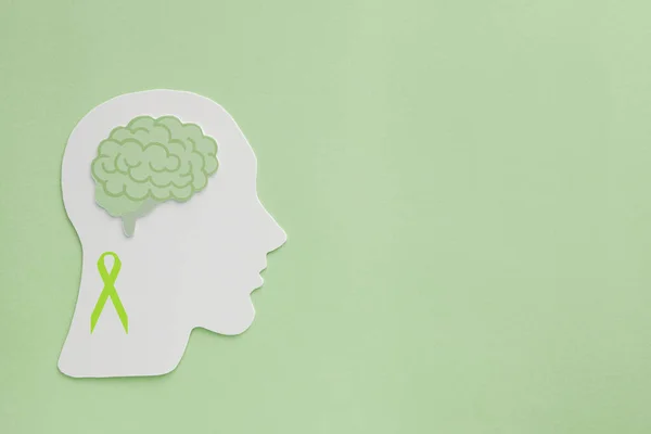 brain paper cutout on green background,  mental health concept, world mental health day