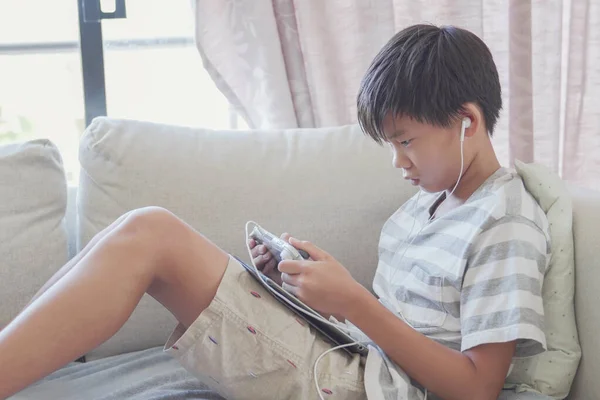 young preteen Asian boy playing game console, social distancing, isolation, addict impact concept