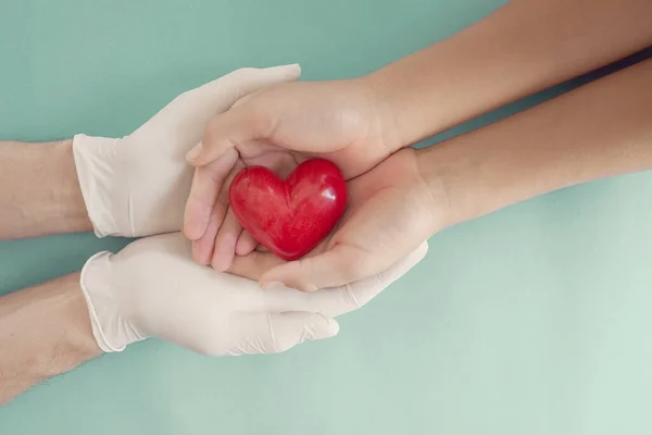 Врач Руки Медицинских Перчатках Держа Ребенка Руки Красное Сердце Медицинское — стоковое фото
