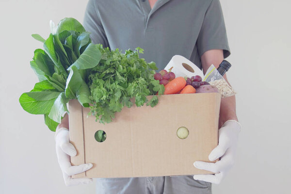 Человек в перчатках, доставляющий еду, волонтер, держащий коробку с продуктами для пожертвований, поддерживающий местную бизнес-концепцию
