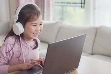 Evde bilgisayarla görüntülü arama yapan bir kız, zoom online sınıf toplantısı uygulaması, sosyal uzaklık, evde eğitim, covid-19 Coronavirus sırasında uzaktan öğrenme, yeni normal kavram