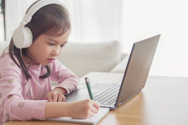 Evde bilgisayarla görüntülü arama yapan bir kız, zoom online sınıf toplantısı uygulaması, sosyal uzaklık, evde eğitim, covid-19 Coronavirus sırasında uzaktan öğrenme, yeni normal kavram