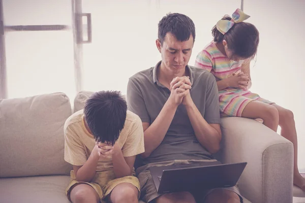 Children praying with father parent with laptop, family and kids worship online together at home, streaming church service, social distancing concept