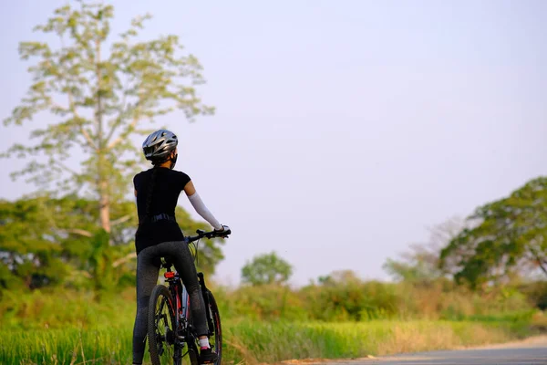 sportive girl rides a bike on the road on the nature background