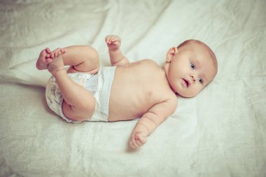 beyaz sayfa üzerinde yalan ve bacaklarını tutan mutlu bebek