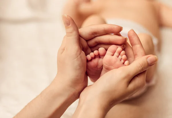 Madre sosteniendo diminuto pie del bebé recién nacido — Foto de Stock