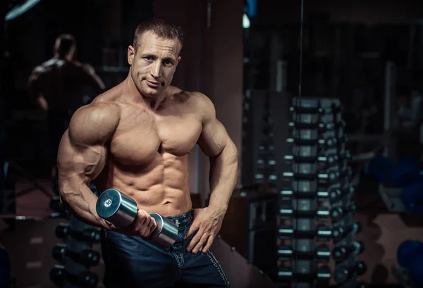 Muscular athletic bodybuilder fitness model posing after exercises in gym — Stock Photo, Image