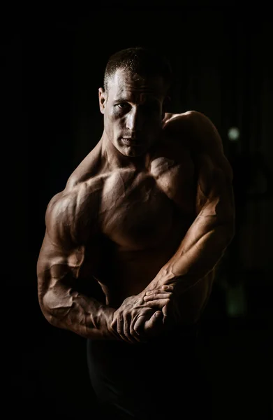 ボディービルダーの筋肉男が黒の背景上のダンベルのエクササイズ — ストック写真
