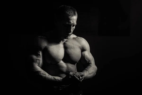 Muscular bodybuilder guy doing exercises with dumbbell over black background — Stock Photo, Image