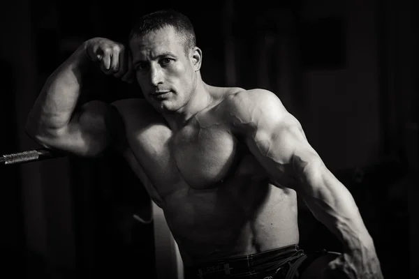 Muscular bodybuilder guy doing exercises with dumbbell over black background — Stock Photo, Image