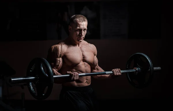 Siyah arka plan üzerinde halter alıştırmalar yapan kaslı vücut geliştirmeci adam — Stok fotoğraf