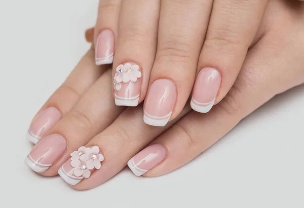 Cuidados com as unhas e manicure. Closeup de belas mãos femininas aplicando o prego transparente polonês em unhas naturais saudáveis das mulheres no salão de beleza. Manicure mão pintura clientes unhas. Alta resolução — Fotografia de Stock