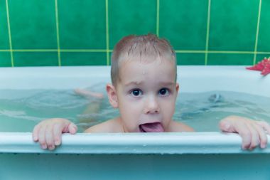 Beyaz arka planda beyaz küvetli bir çocuk.