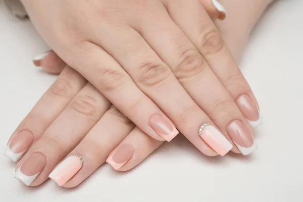 Handen met gemanicuurde nagels bedekt met roze nagellak op bont achtergrond — Stockfoto