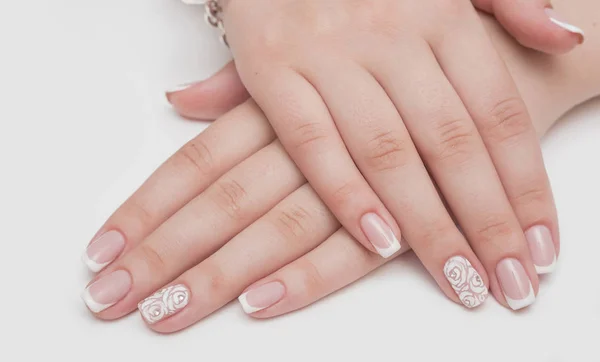 Manicure met steentjes in de vorm van harten en roze ballen op witte en rode nagellak op een witte achtergrond. — Stockfoto