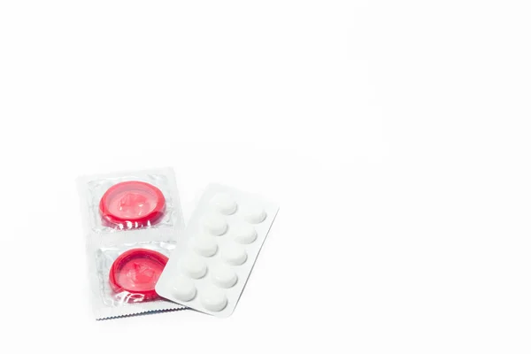 Condoms and birth control pills on a white background — Stock Photo, Image