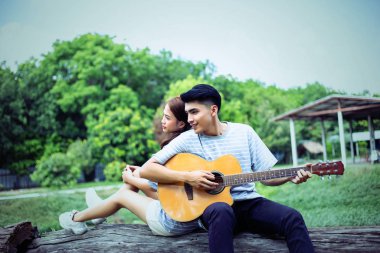 Kız arkadaşı için açık tuğla duvara gitar hipster adam birlikte zevk.