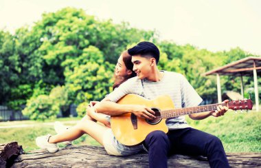 Kız arkadaşı için açık tuğla duvara gitar hipster adam birlikte zevk.