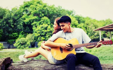 Kız arkadaşı için açık tuğla duvara gitar hipster adam birlikte zevk.