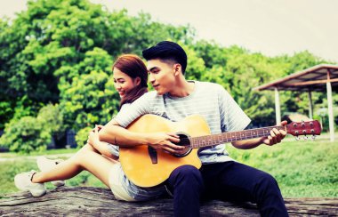 Kız arkadaşı için açık tuğla duvara gitar hipster adam birlikte zevk.