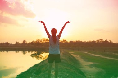 Gün batımında güçlü kendine güvenen kadın kollarını aç.. 
