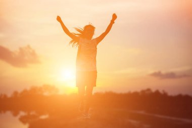 Gün batımında güçlü kendine güvenen kadın kollarını aç.. 