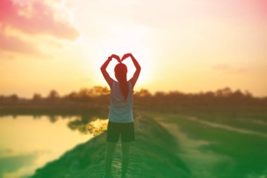 Gün batımında güçlü kendine güvenen kadın kollarını aç.. 