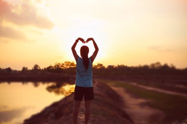 Gün batımında güçlü kendine güvenen kadın kollarını aç.. 
