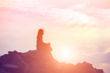 Güzel bir arka plan için dua eden bir kadın silueti.