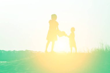 Gün batımının önünde mutlu bir genç kızın silueti.