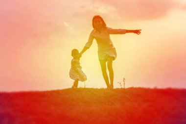 Anne kucağında bebekle gün batımında yürüyor..