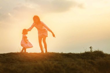 Anne kucağında bebekle gün batımında yürüyor..