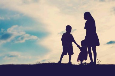 Anne kucağında bebekle gün batımında yürüyor..