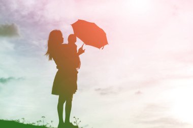 Anne kucağında bebekle gün batımında yürüyor..