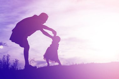 Anne kucağında bebekle gün batımında yürüyor..