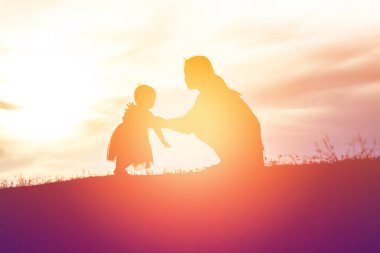 Anne kucağında bebekle gün batımında yürüyor..