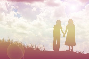 Birbirine bakan iki kızın silueti el ele tutuşuyor.