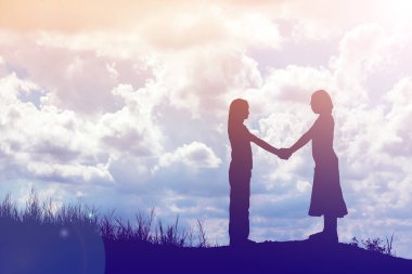 Birbirine bakan iki kızın silueti el ele tutuşuyor.