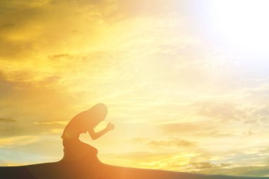 silhouette of woman praying over beautiful sky background