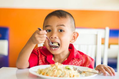 Küçük tatlı çocuk, öğle yemeği için evde spagetti yiyor, lezzetli yemekler yiyor.