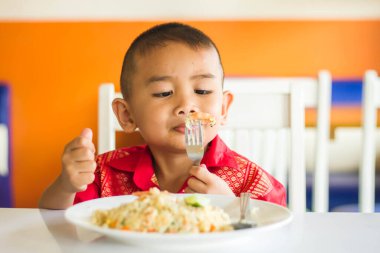 Küçük tatlı çocuk, öğle yemeği için evde spagetti yiyor, lezzetli yemekler yiyor.