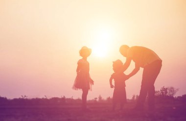 Mutlu bir ailenin silueti ve mutlu gün batımı