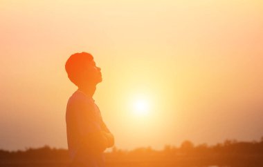 Güzel bir arka plan için dua eden bir adamın silueti.