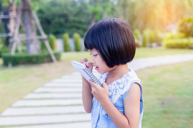 Bulanık yeşil arka planda mutlu tatlı kız çocuğu.